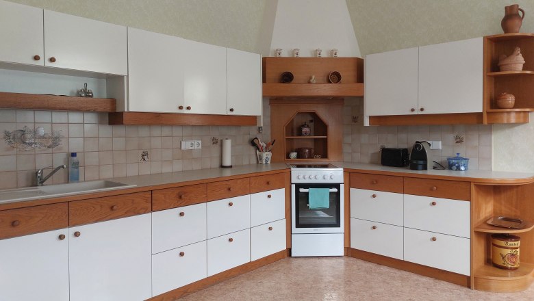 Küche mit weißen und holzfarbenen Schränken, Herd und Spüle.