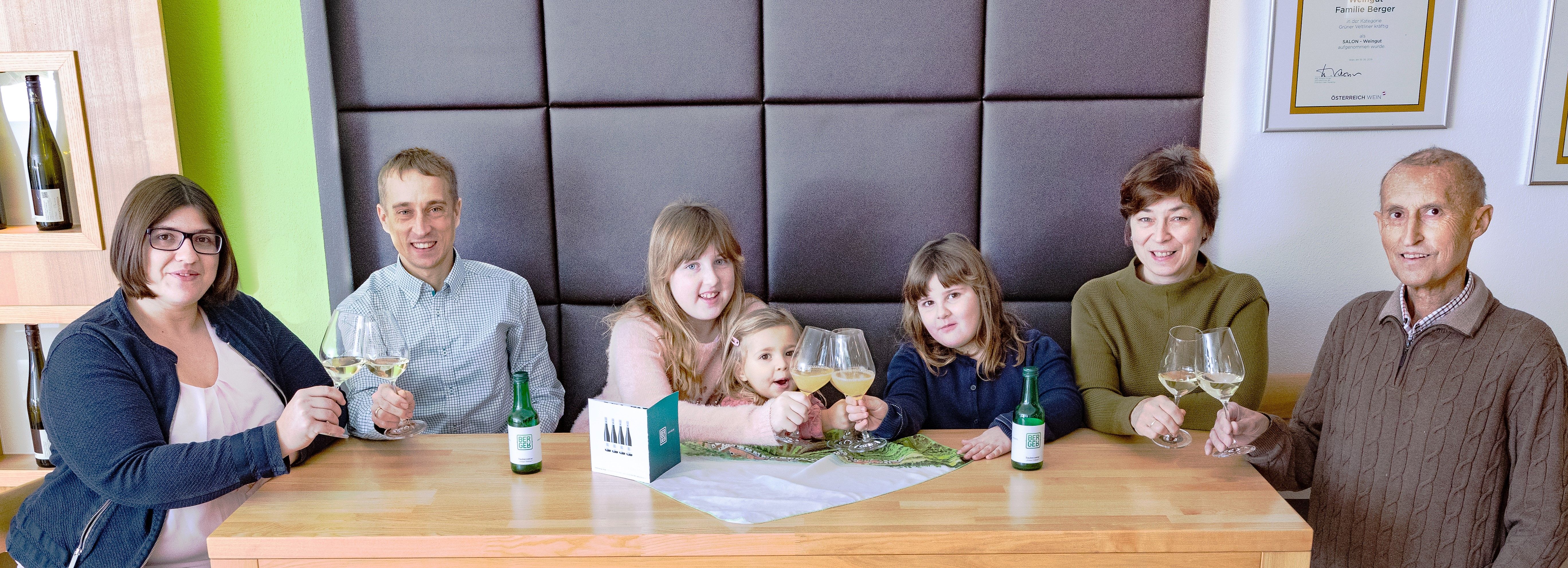 Group of people sitting at a table with wine glasses in a tasting room.