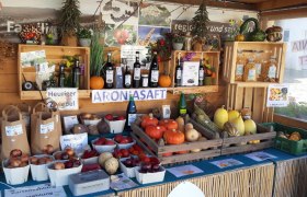 Ein Verkaufsstand mit regionalen Produkten wie K&uuml;rbissen, Zwiebeln und Aroniasaft.
