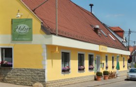 Gelbes Landgasthaus mit roten Dachziegeln und Blumenkästen vor den Fenstern.