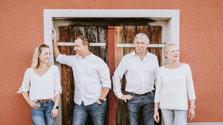 Vier Personen stehen vor einer Holzt&uuml;r, alle in wei&szlig; gekleidet.