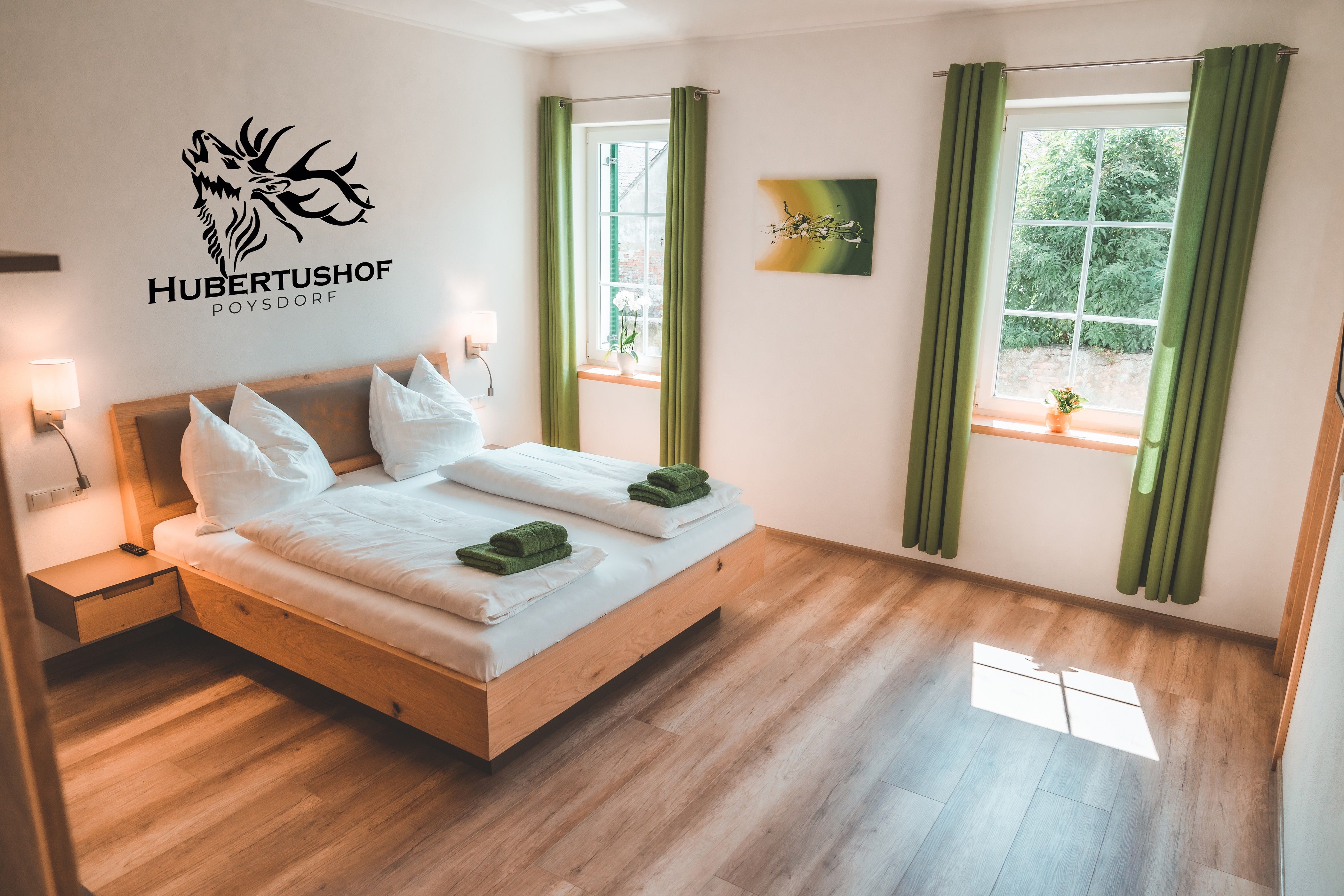 Modern guest room with double bed, green curtains and wall decoration at Hubertushof Poysdorf.