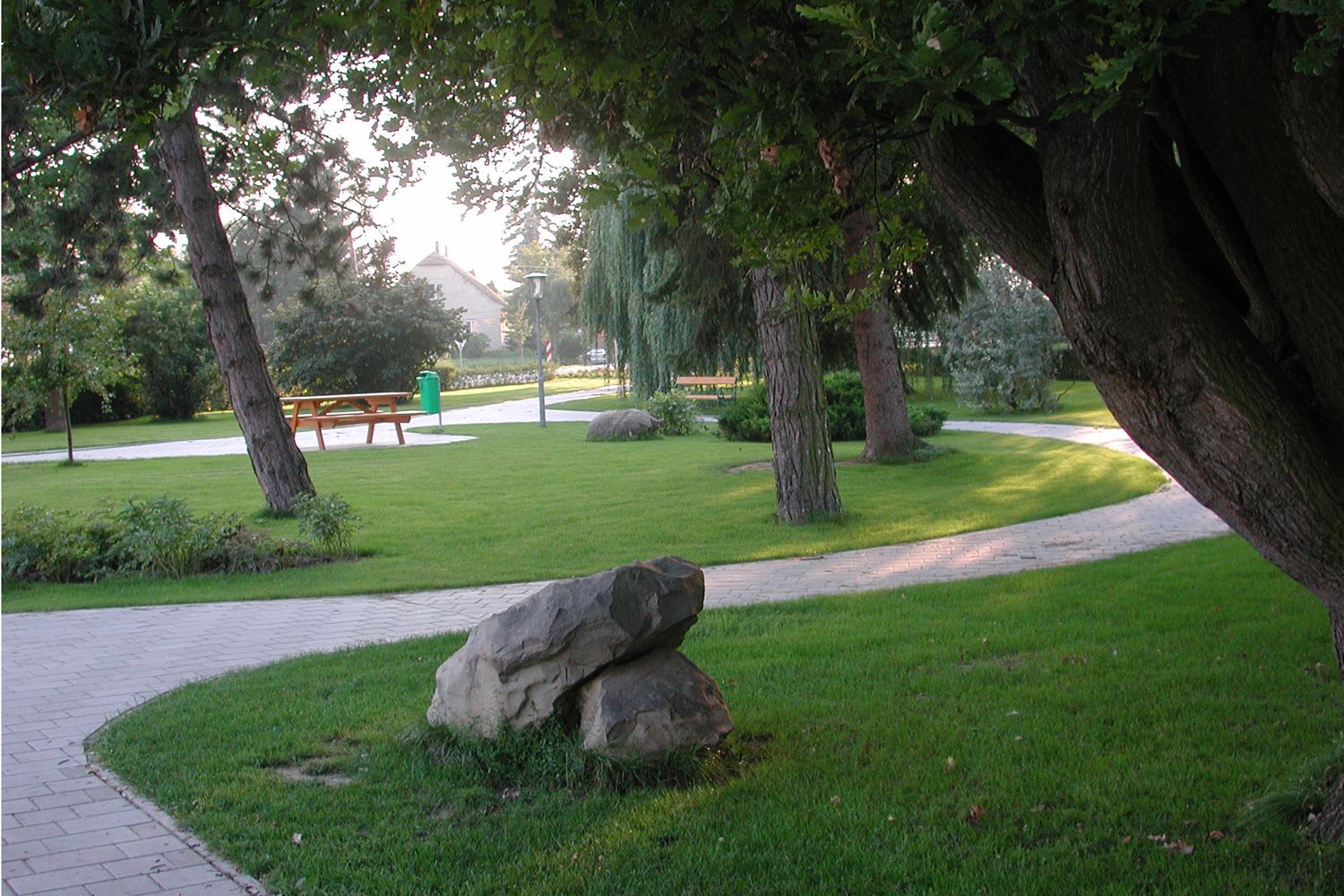 Ein gepflegter Park mit Bäumen, Wegen und Bänken.