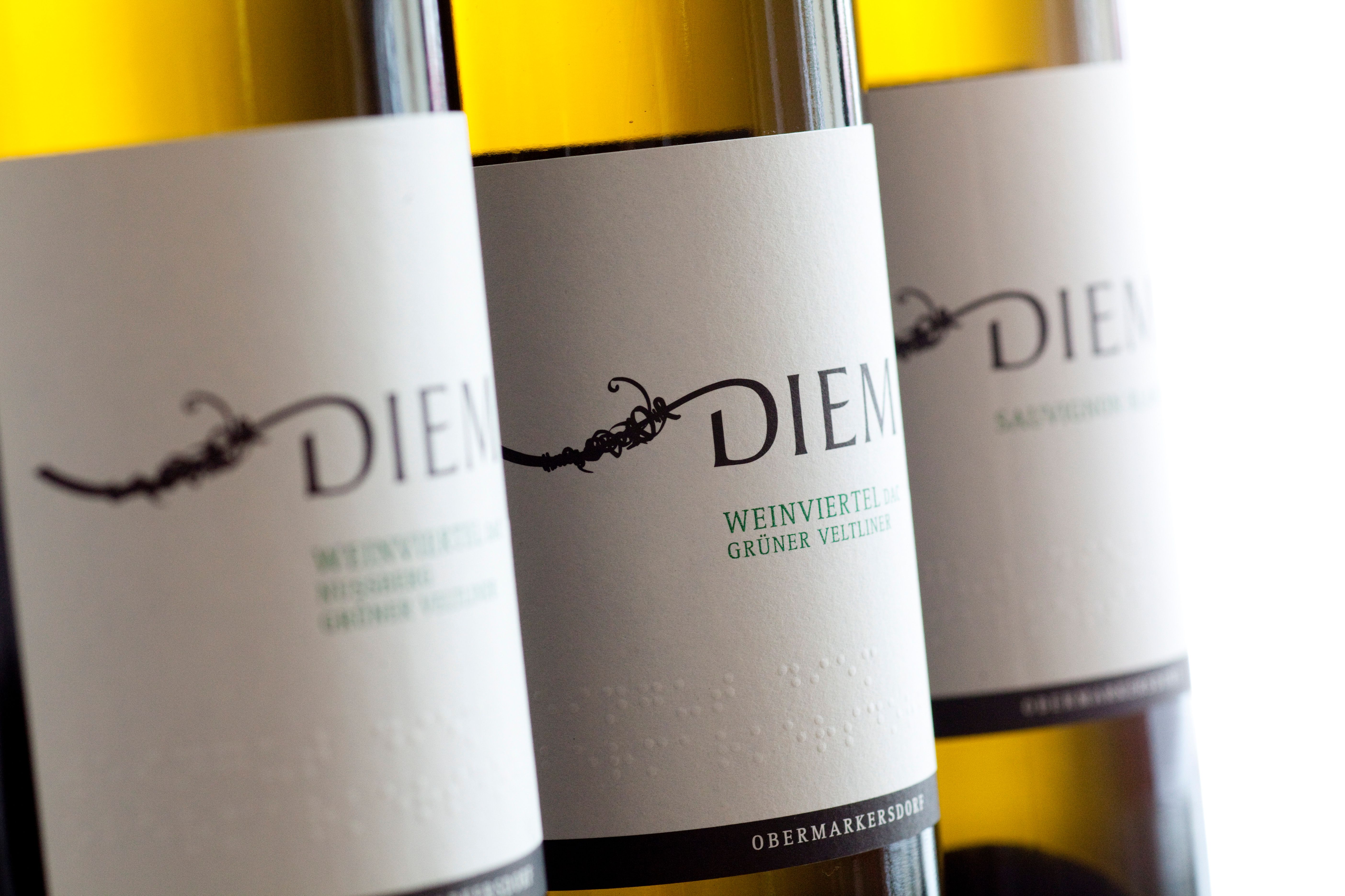 Detailní záběr lahví vína Diem s etiketami pro veltlínské zelené a Sauvignon Blanc.