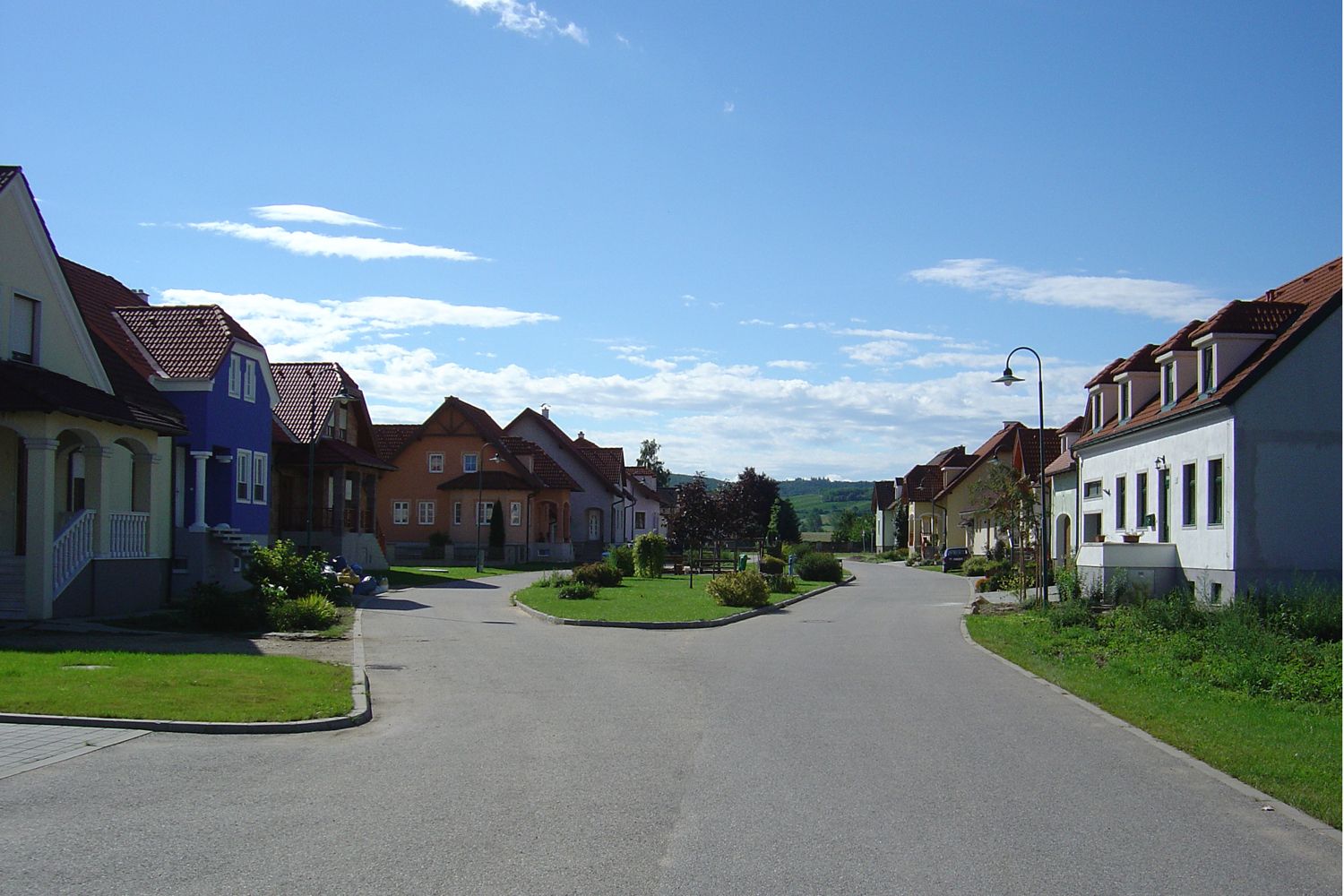 Straße in Alberndorf mit bunten Häusern und blauen Himmel.