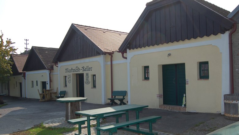 Traditionelle Weinkeller mit Holzbänken und Tischen im Freien.