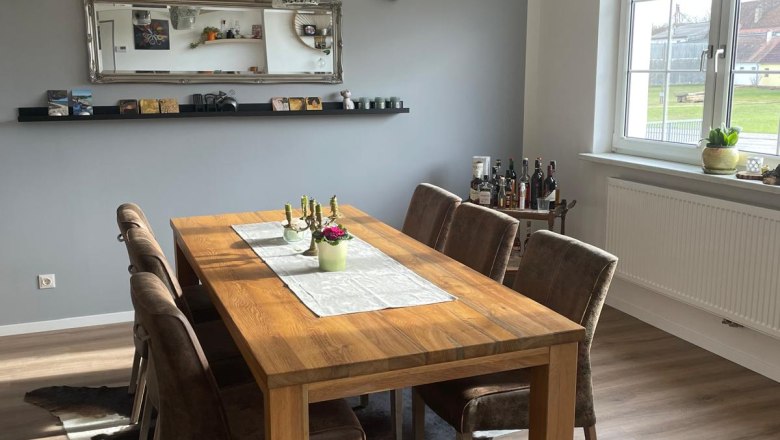 Essbereich mit Holztisch, sechs St&uuml;hlen, Spiegel und Fenster.