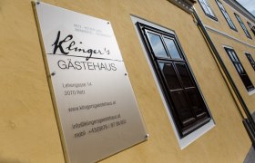 Schild von Klinger's Gästehaus an einer gelben Hauswand.