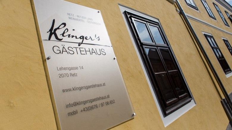 Schild von Klinger's G&auml;stehaus an einer gelben Hauswand.