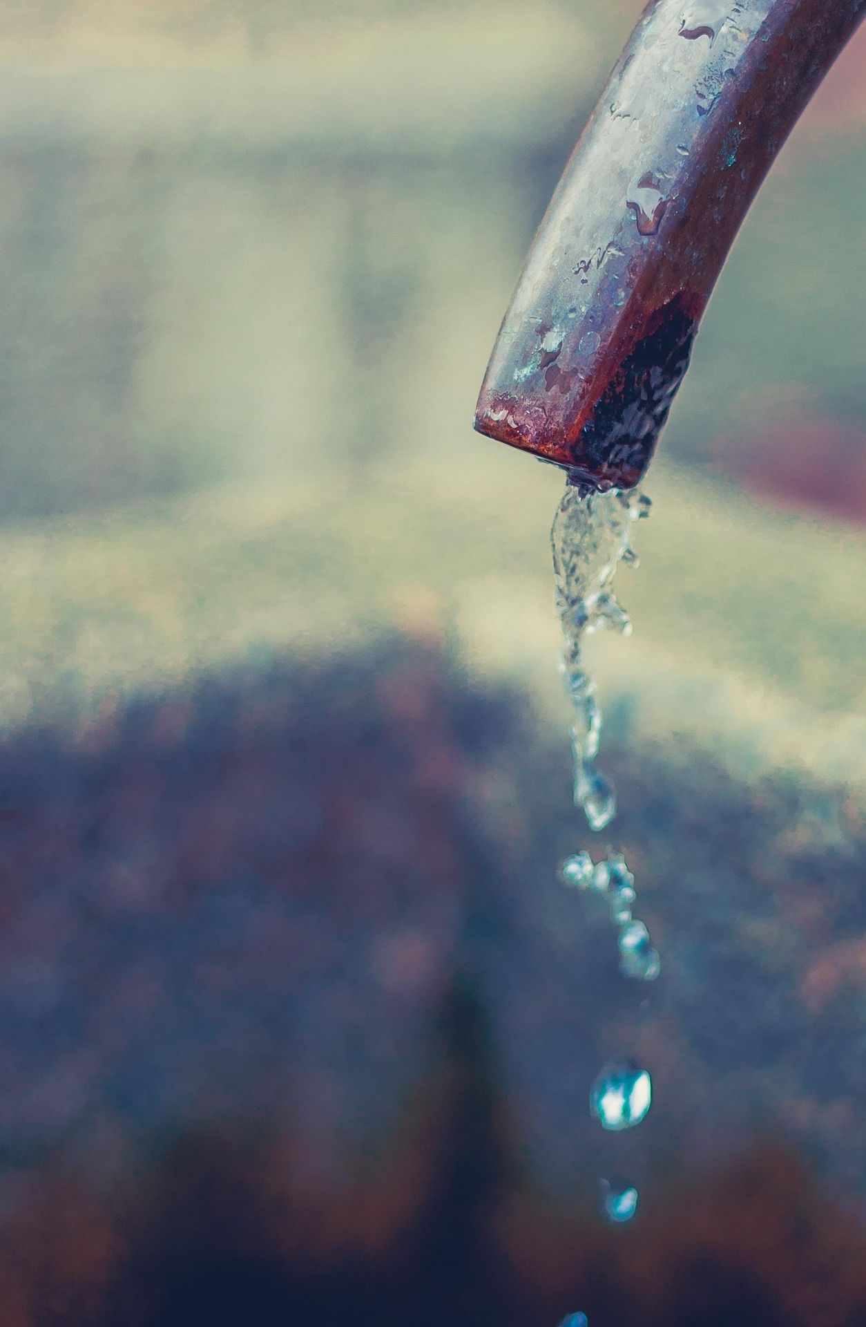 Nahaufnahme eines Trinkbrunnens mit fließendem Wasser aus einem Metallrohr.