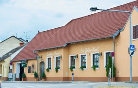Ein traditionelles Gasthaus mit gelber Fassade und rotem Dach, beschriftet mit 'Gasthaus Rammel' und 'Zum Goldenen Engel'.