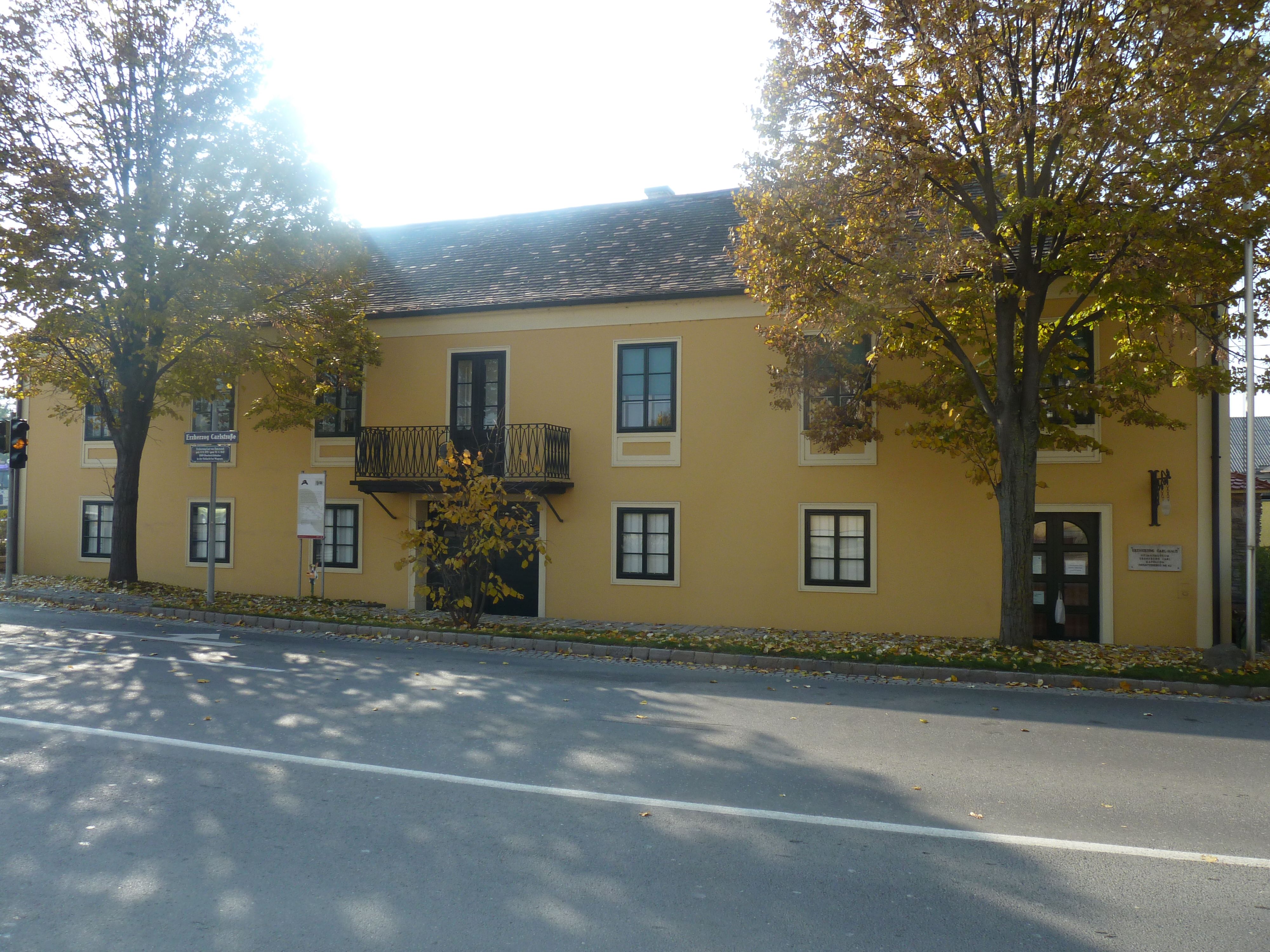 Žltá budova s balkónom a stromami vpredu, Dom arcivojvodu Karola a Napoleonovo múzeum v Deutsch-Wagrame.