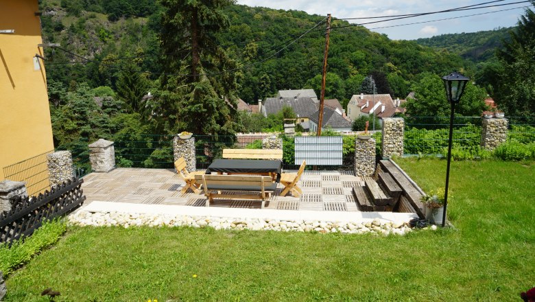 Pension Thayatalblick, © Jörg Riffer Terrasse mit Holzmöbeln und Blick auf ein Dorf und bewaldete Hügel.