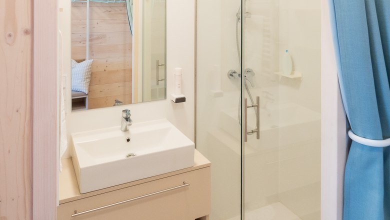 Modernes Badezimmer mit Waschbecken, Spiegel, Dusche und blauen Vorhängen.