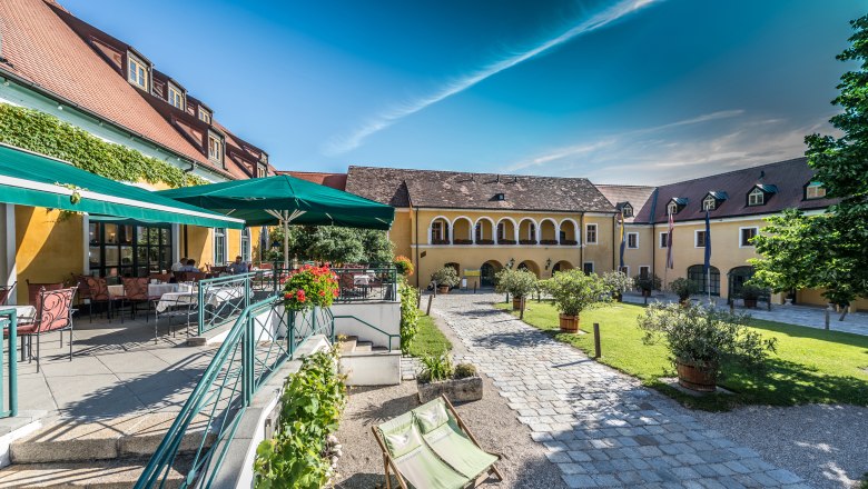 Innenhof des Althof Retz mit Terrasse, Sonnenschirmen und Gartenm&ouml;beln.