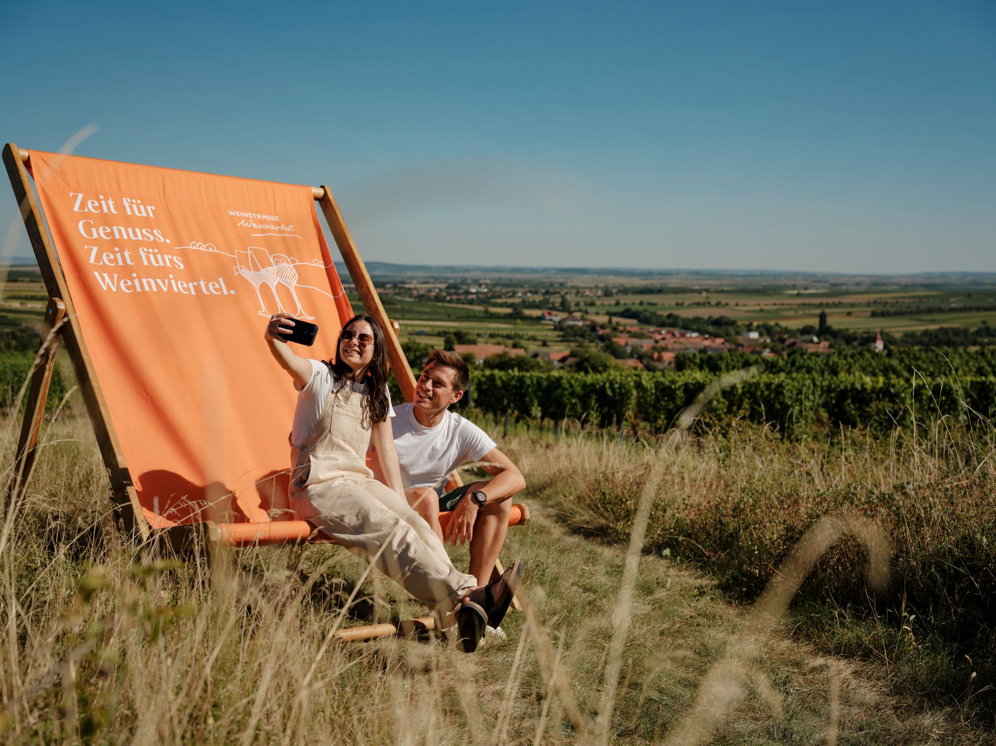 Paar im Liegestuhl in den Weinbergen der Weinstraße Weinviertel West mit Blick über die Landschaft