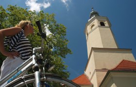 Frau mit Fahrrad vor der Wallfahrtskirche Maria Moos.
