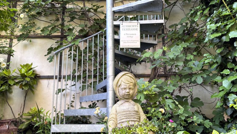 Steintreppe im Garten mit Pflanzen und Statue eines Kindes.