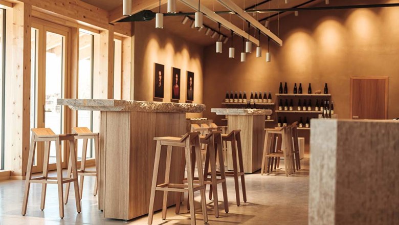 Interior view of a modern tasting room with wooden furniture and wine bottle racks.