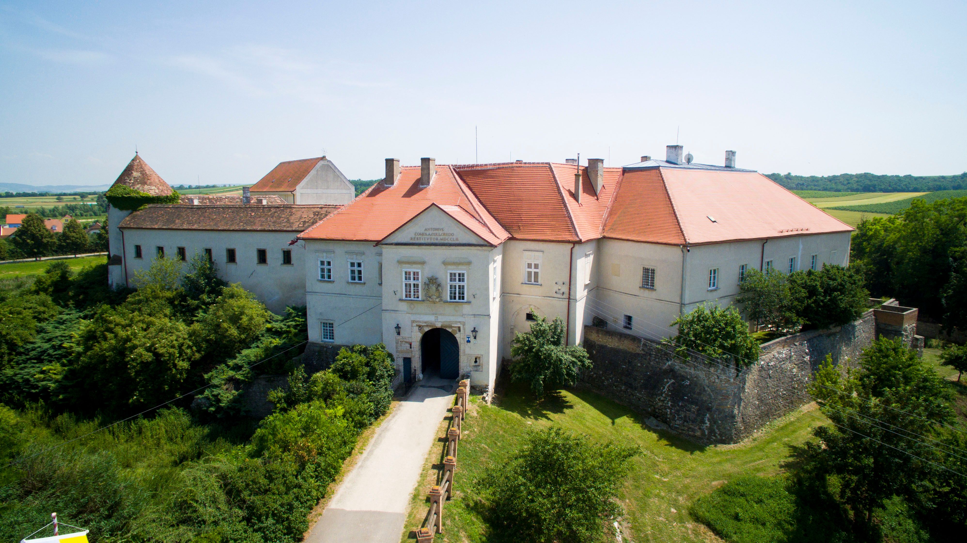 Luftaufnahme von Schloss Mailberg mit roten Dächern und umgebender Landschaft.