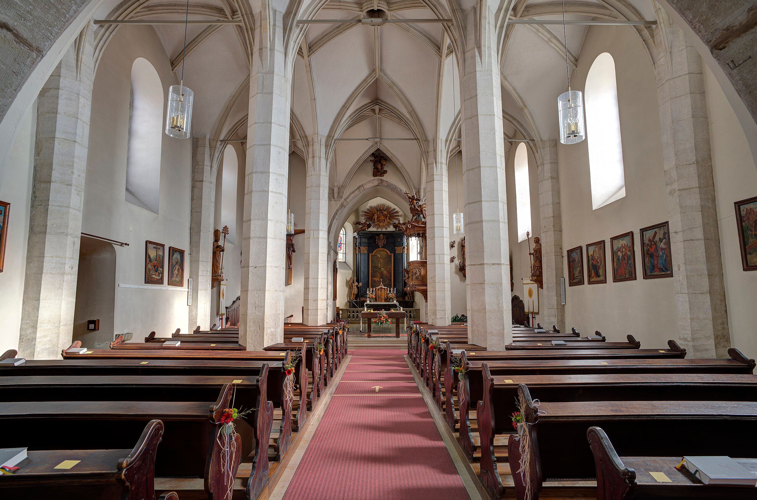 An interior view of a church with pews, an altar, and high vaulted ceilings.