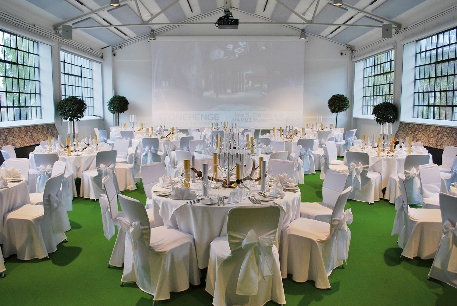 Elegant function room with white tables and a green floor.