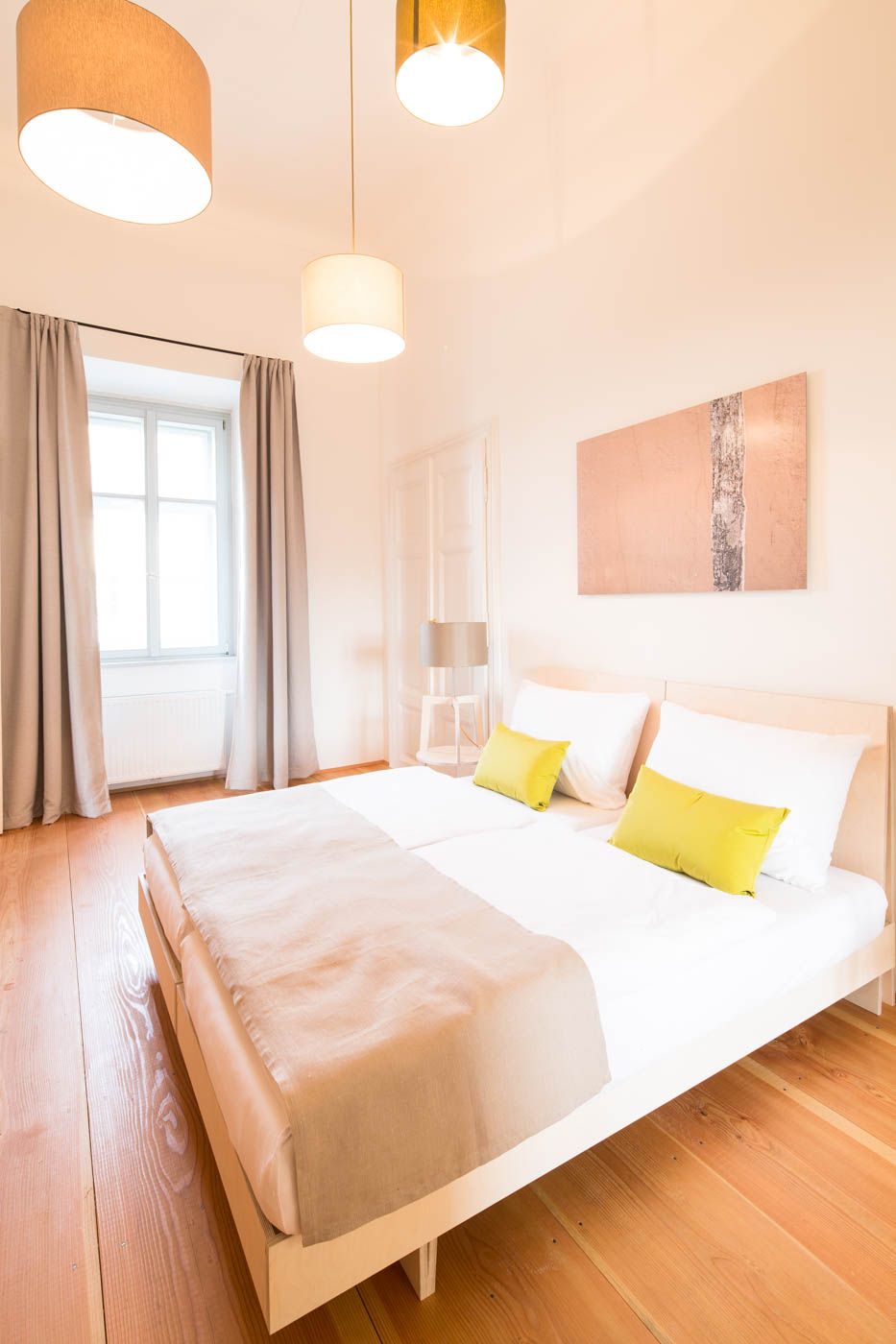 Helles Schlafzimmer mit Doppelbett, Holzboden und modernen Lampen.