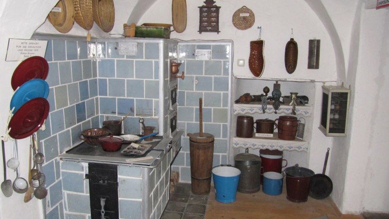 Historische K&uuml;che im S&uuml;dm&auml;hrermuseum mit blau gekacheltem Ofen und traditionellen K&uuml;chenutensilien.