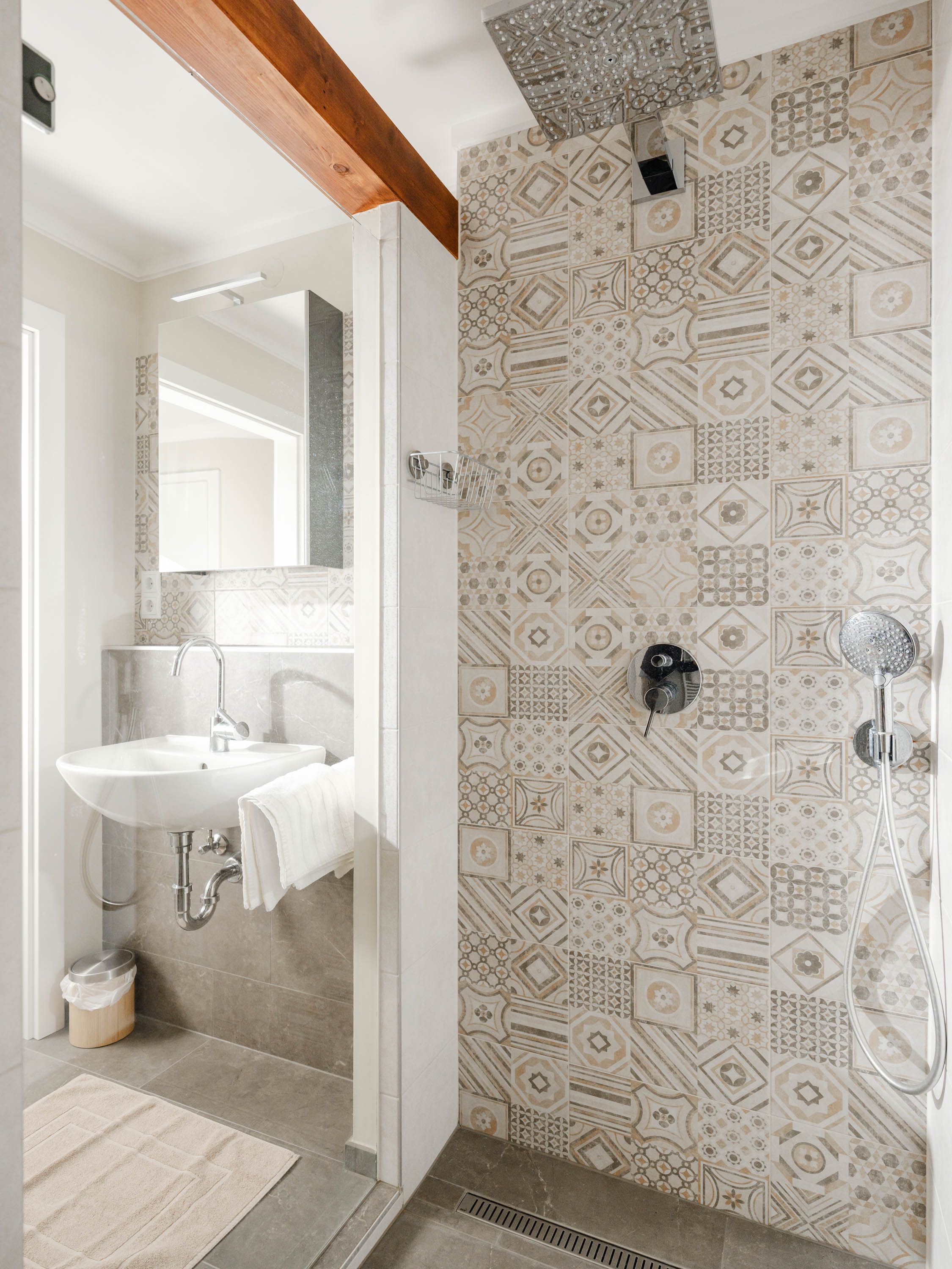 Modernes Badezimmer mit gemusterten Fliesen, Waschbecken und Regendusche.