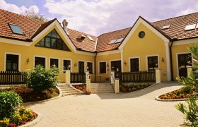 Gelbes Geb&auml;ude mit roten Ziegeld&auml;chern und Garten.