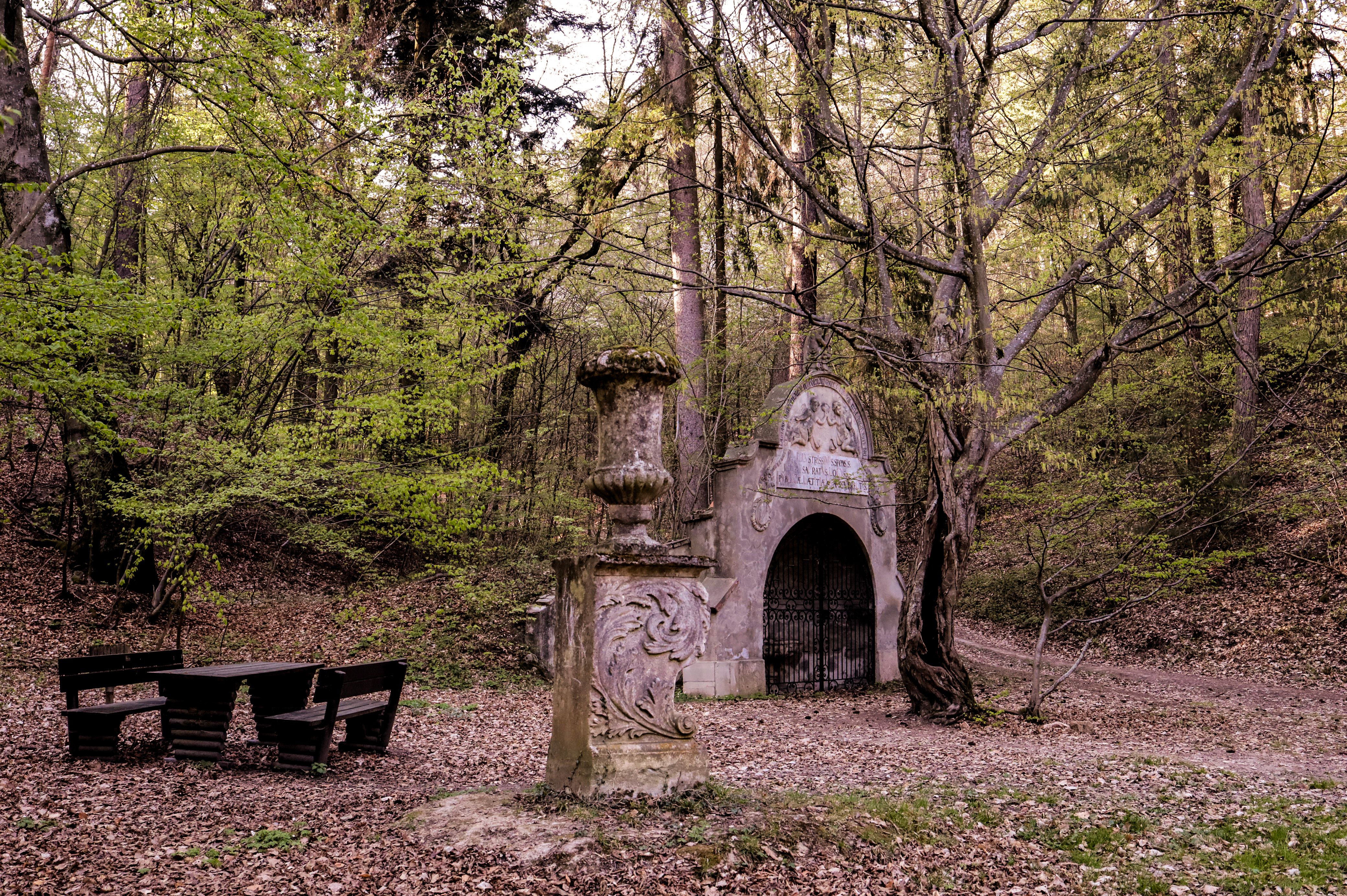 Historic fountain in the forest of Maissau with stone sculpture and picnic table.