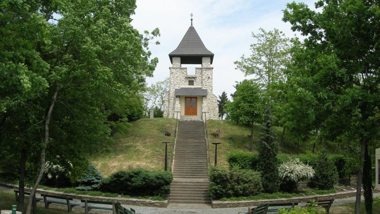 Ein steinernes Kriegerdenkmal mit Turm und Treppe, umgeben von B&auml;umen und B&auml;nken.