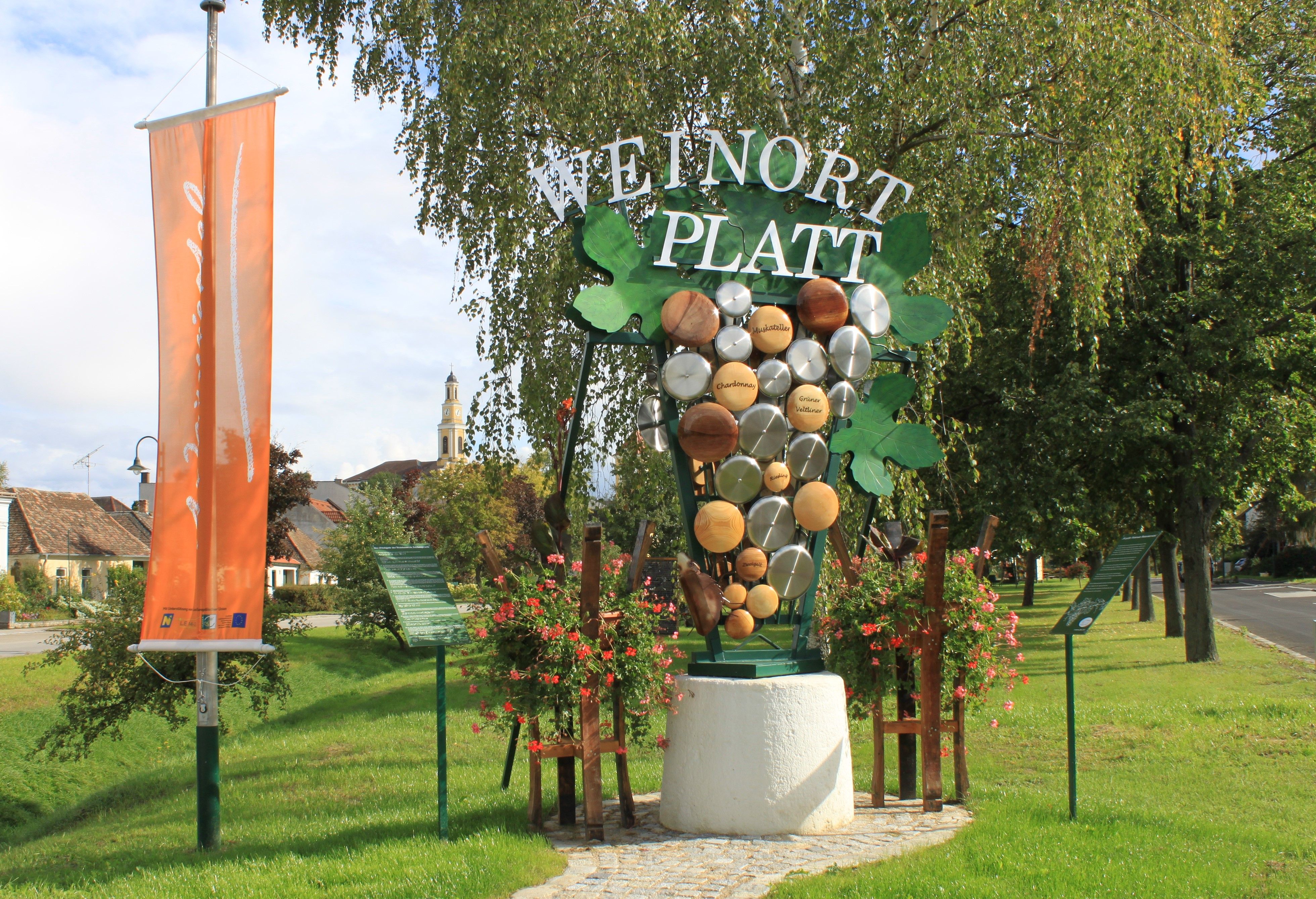 Welcome sign in Platt with grape decoration and church in the background.