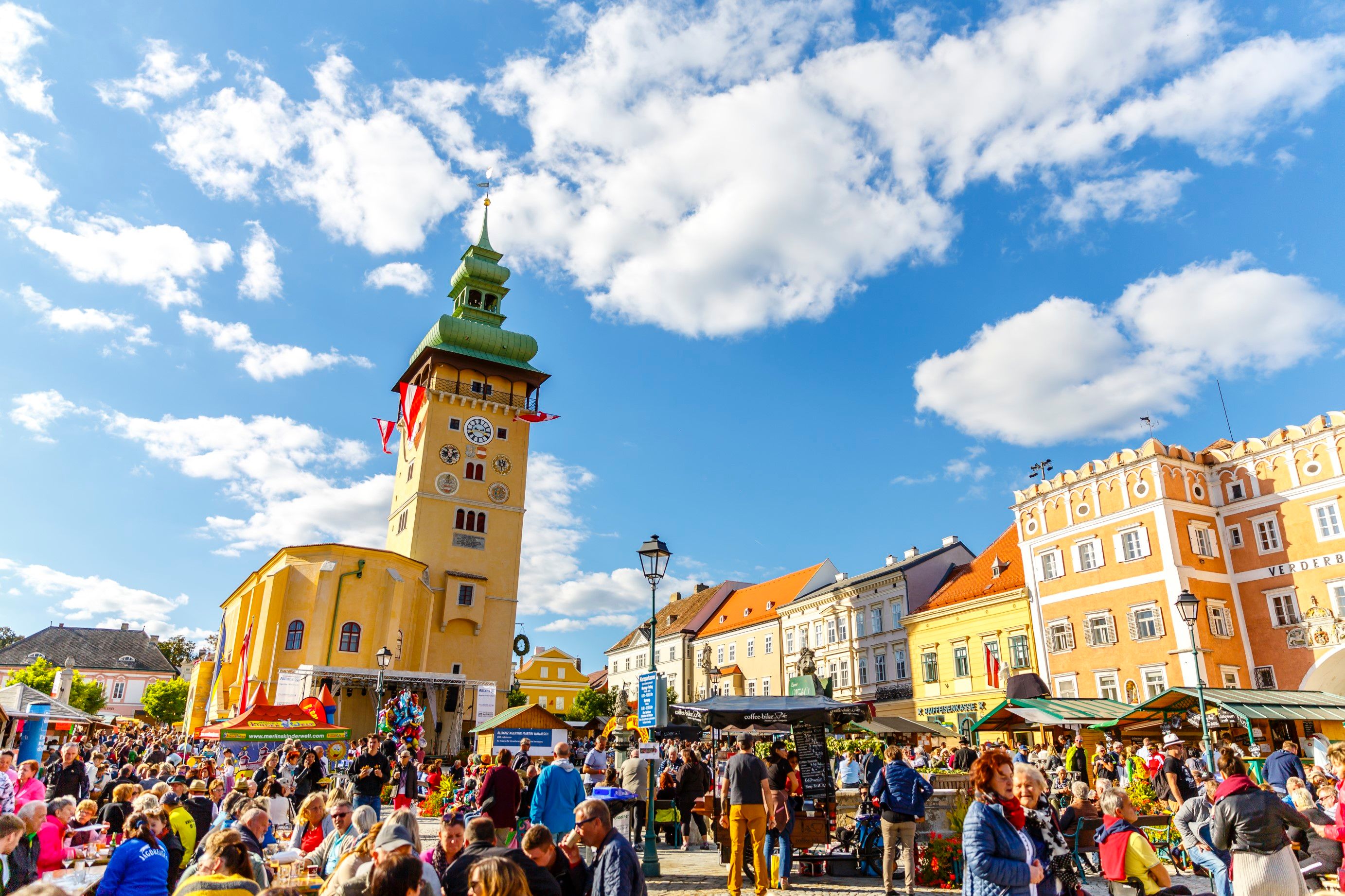 Menschenmenge auf einem belebten Platz in Retz mit einem markanten Uhrturm im Hintergrund.