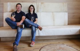 Ein Mann und eine Frau sitzen auf einem Sofa und halten Weingläser in der Hand.