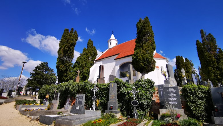 Kunigungenkirche in Mailberg mit Friedhof und blühenden Gräbern im Vordergrund.
