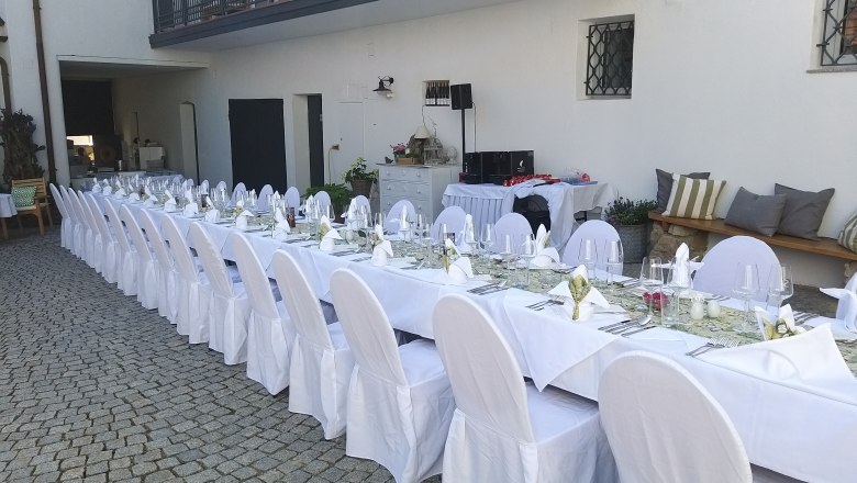 Langer, festlich gedeckter Tisch im Freien mit weißen Tischdecken und Stuhlhussen.