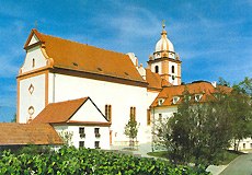 Wallfahrtskirche Maria Roggendorf mit rotem Dach und Turm vor blauem Himmel.
