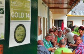 Menschen sitzen an einem langen Tisch in einem überdachten Außenbereich eines Restaurants.