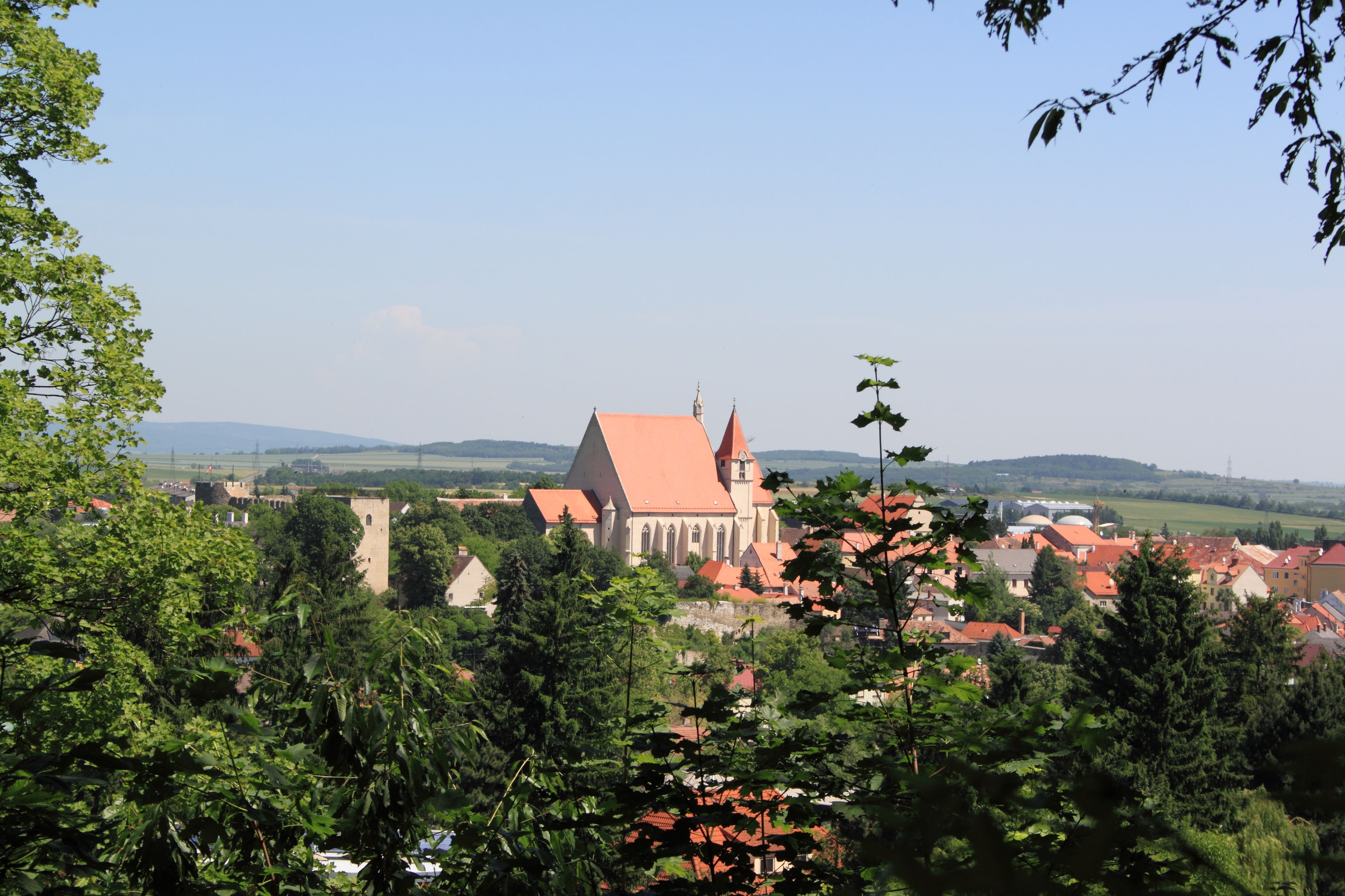 Panoramablick auf Eggenburg mit Kirche und umliegenden Gebäuden, umgeben von Bäumen und Hügeln im Hintergrund.