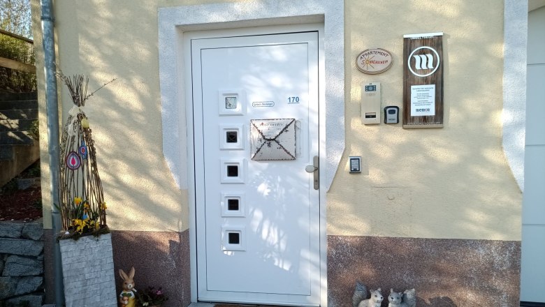 Eingangsbereich eines Hauses mit dekorativen Elementen wie einem Hasen, einem Willkommensschild und Blumen.