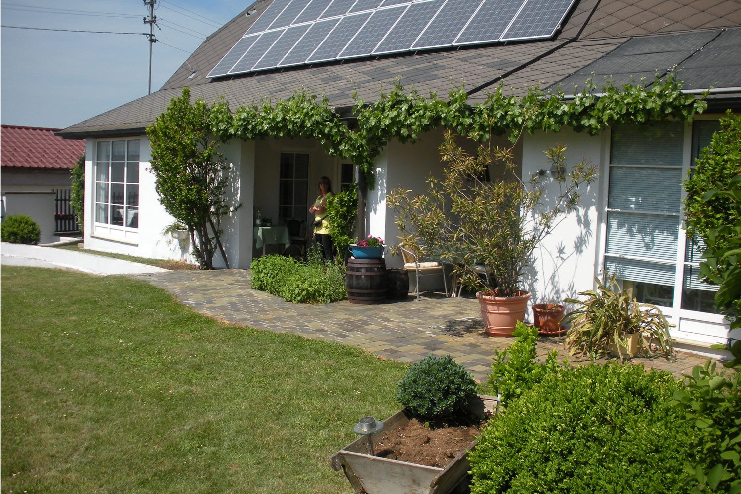 Haus mit Solarpanelen und Garten im Vordergrund.