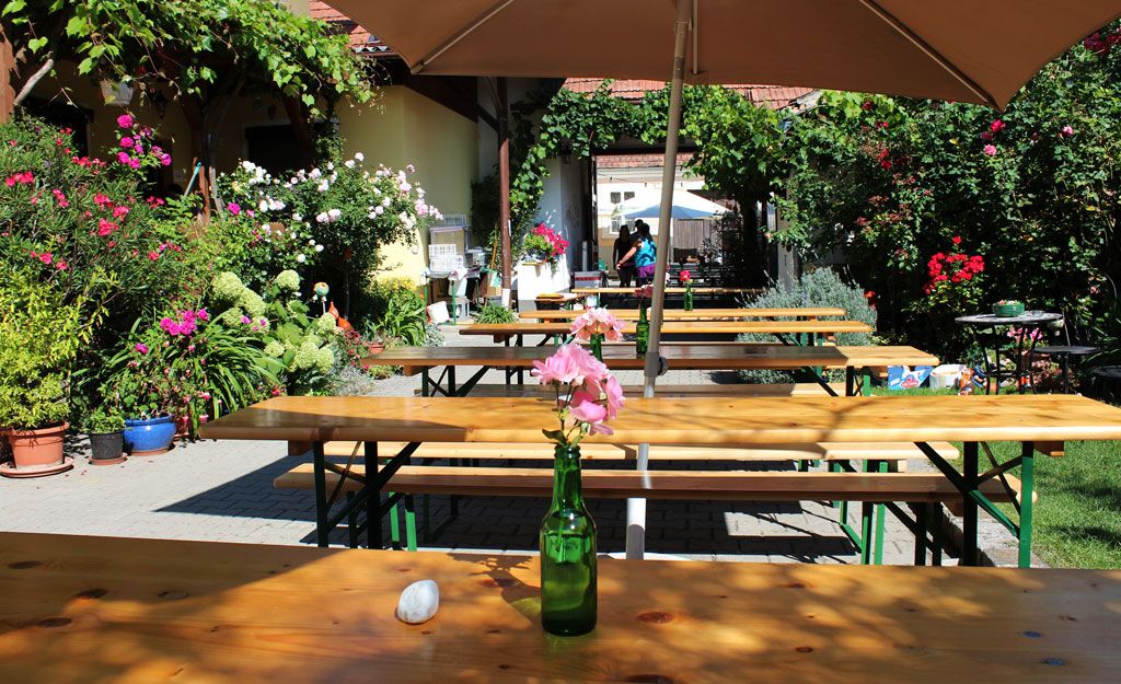A sunny garden with wooden benches, flowers and a parasol.