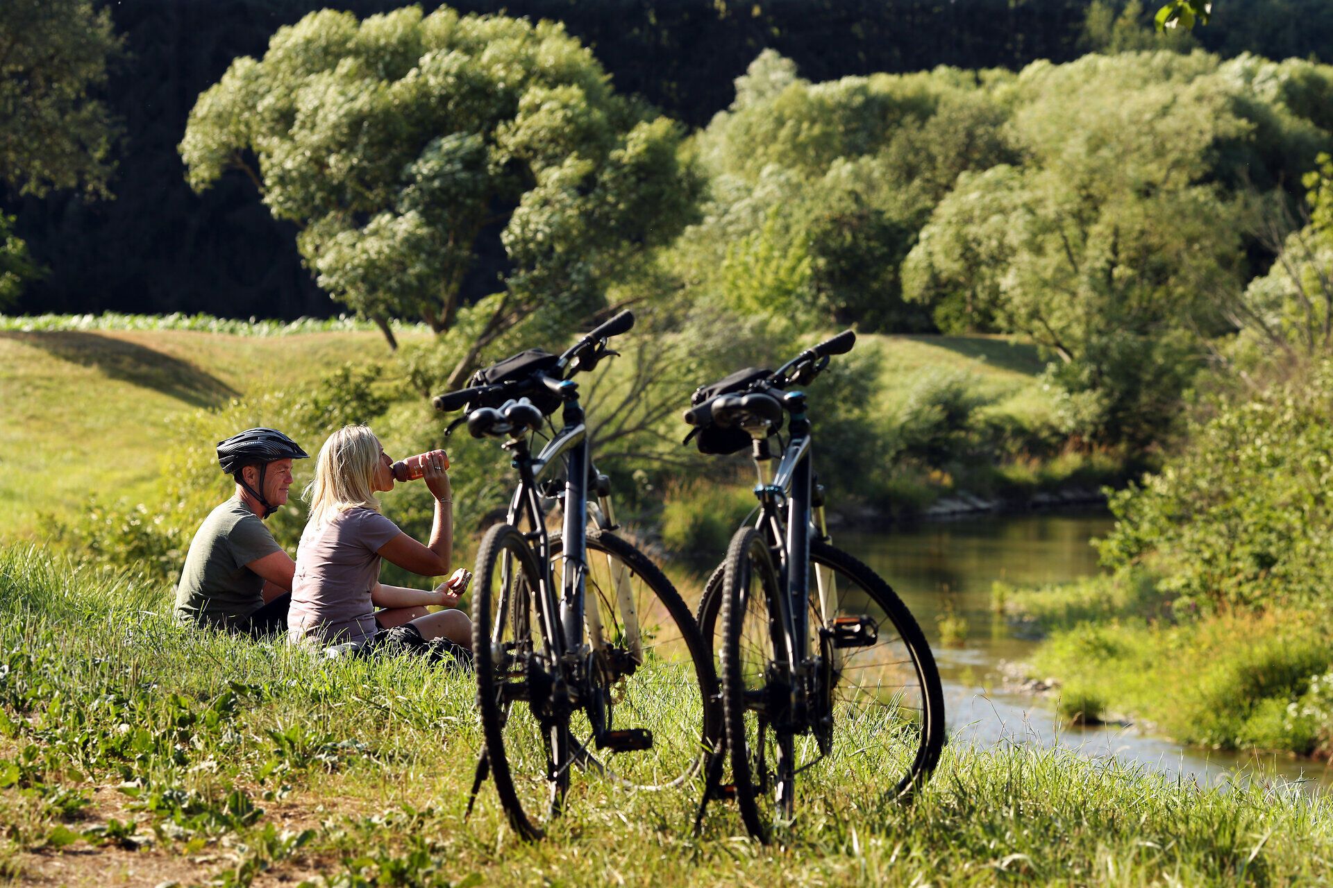 Pärchen macht kurze Pause vom Radfahren am Wasser.