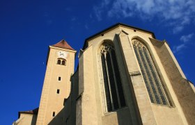Ansicht der Hl. Blutkirche in Pulkau mit Turm und gotischen Fenstern vor blauem Himmel.