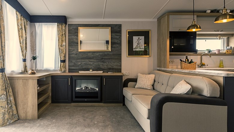 Gemütliches Wohnzimmer mit Sofa, Kamin, Spiegel und Küche.