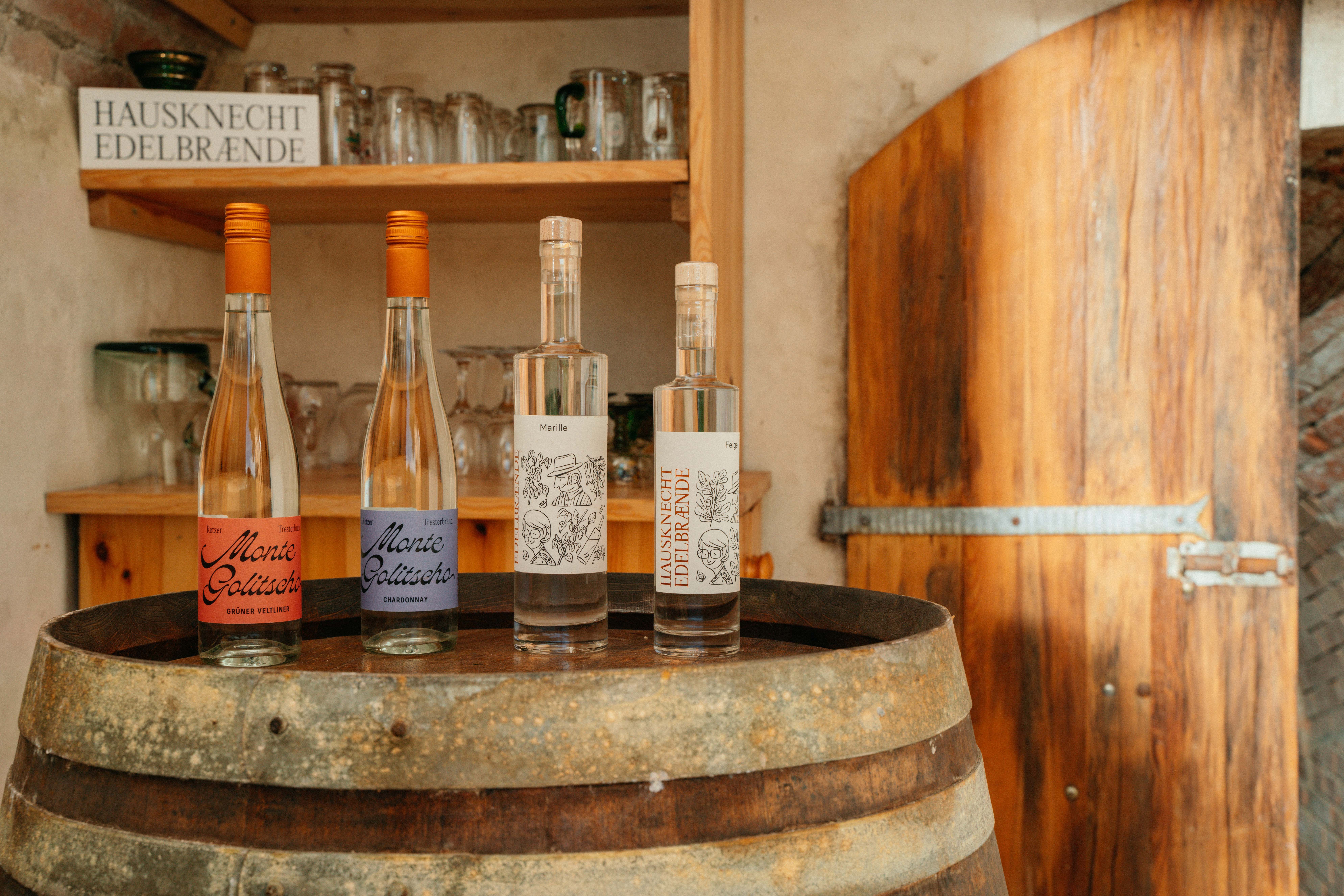 Tri fľaše brandy na drevenom sude v rustikálnej miestnosti.