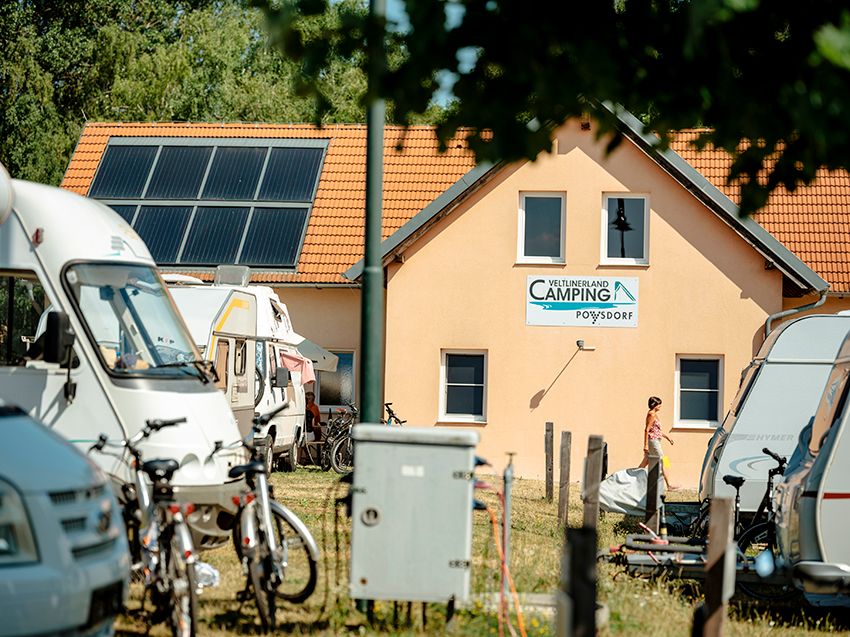 Campingplatz mit Wohnmobilen und Sanitärgebäude im Hintergrund.
