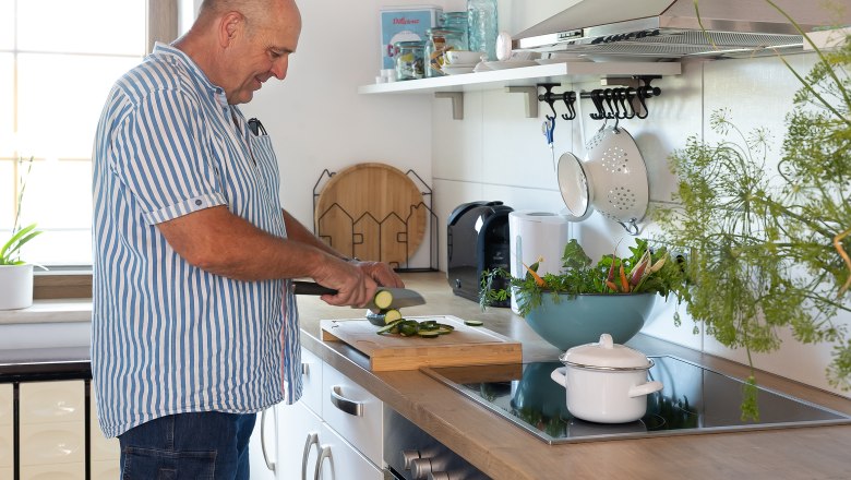 Mann schneidet Gemüse in moderner Küche.