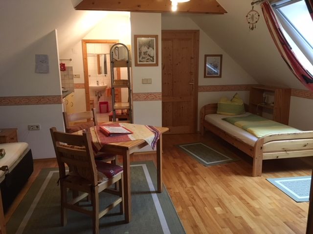 Gemütliche Ferienwohnung mit Holzmöbeln, zwei Betten, Esstisch und Dachfenster.